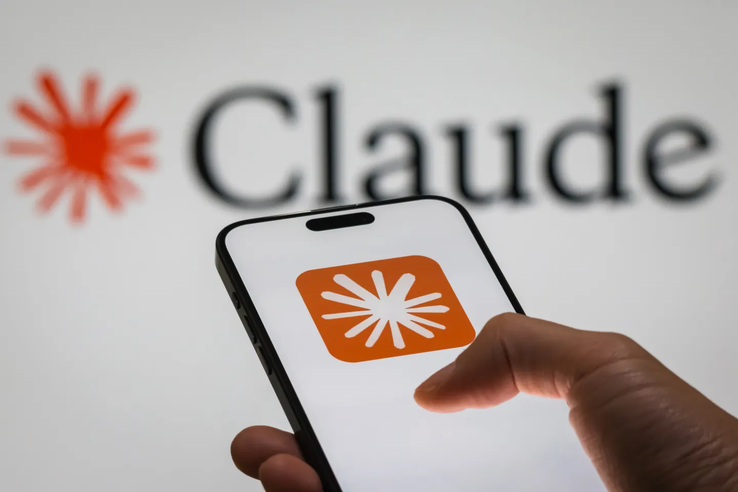 Anthropic's chatbot Claude shown on a phone with the logo in the background.